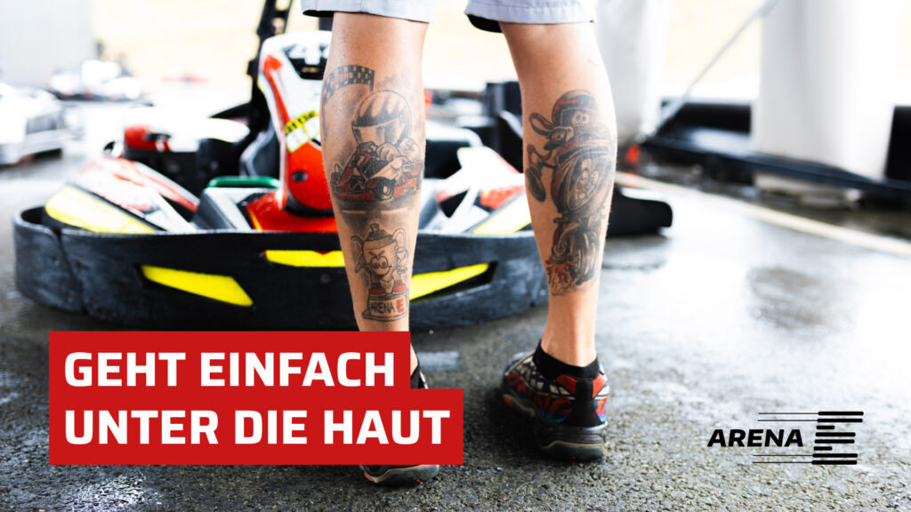 Die mit Karts tätowierten Beine eines Mitarbeiters der Arena E, im Hintergrund ist ein schwarz-gelbes Kart zu sehen